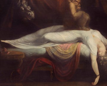 A woman lies collapsed across a red-covered bed.